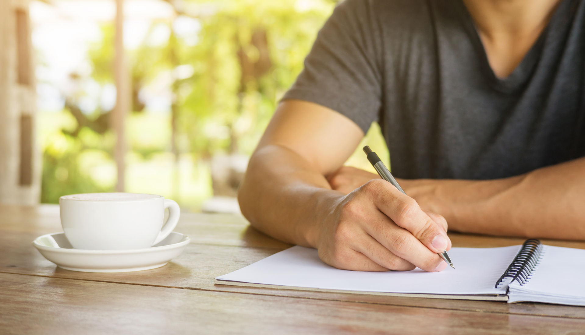 Zu sehen ist eine Hand mit Stift beim Notieren in ein Heft