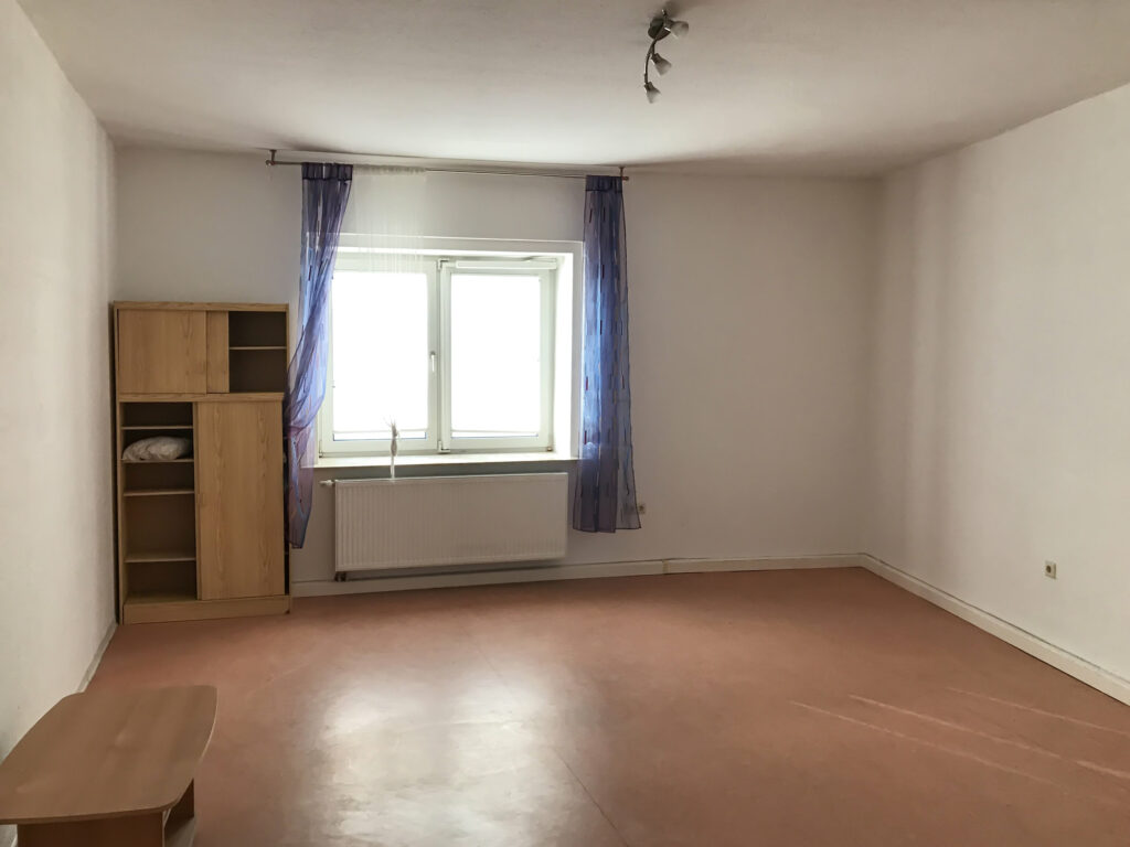 Übergangswohnung, Zimmer mit Schrank und Tisch