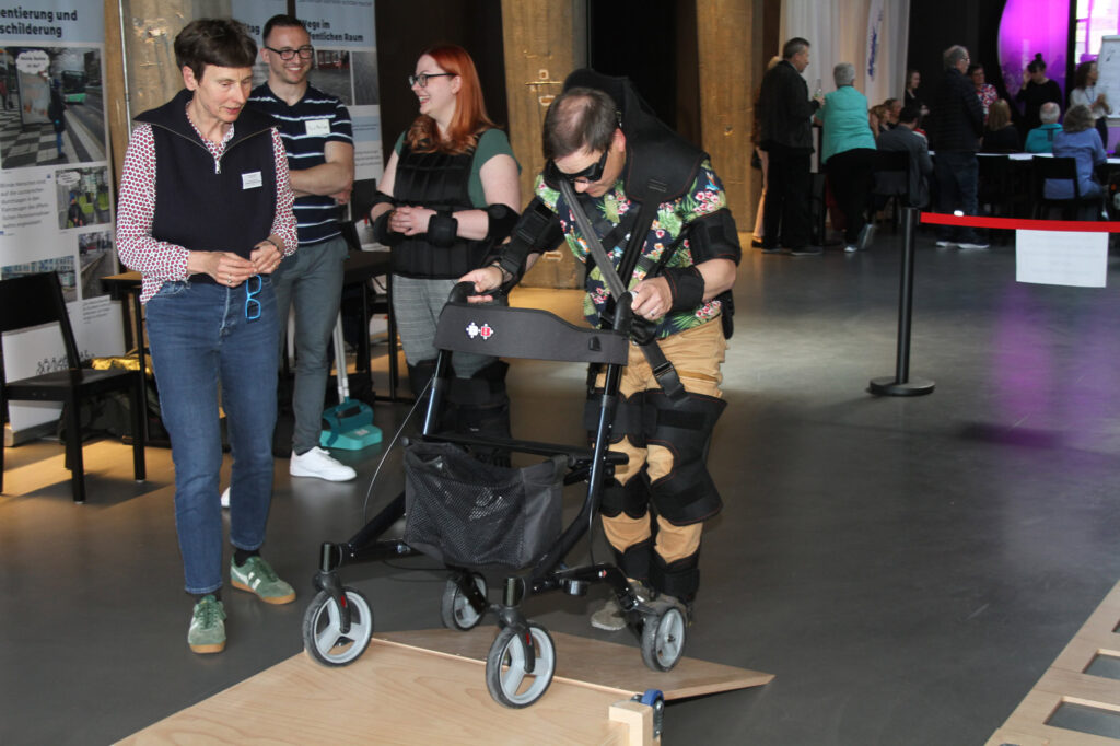Besucher mit Altersimulationsanzug