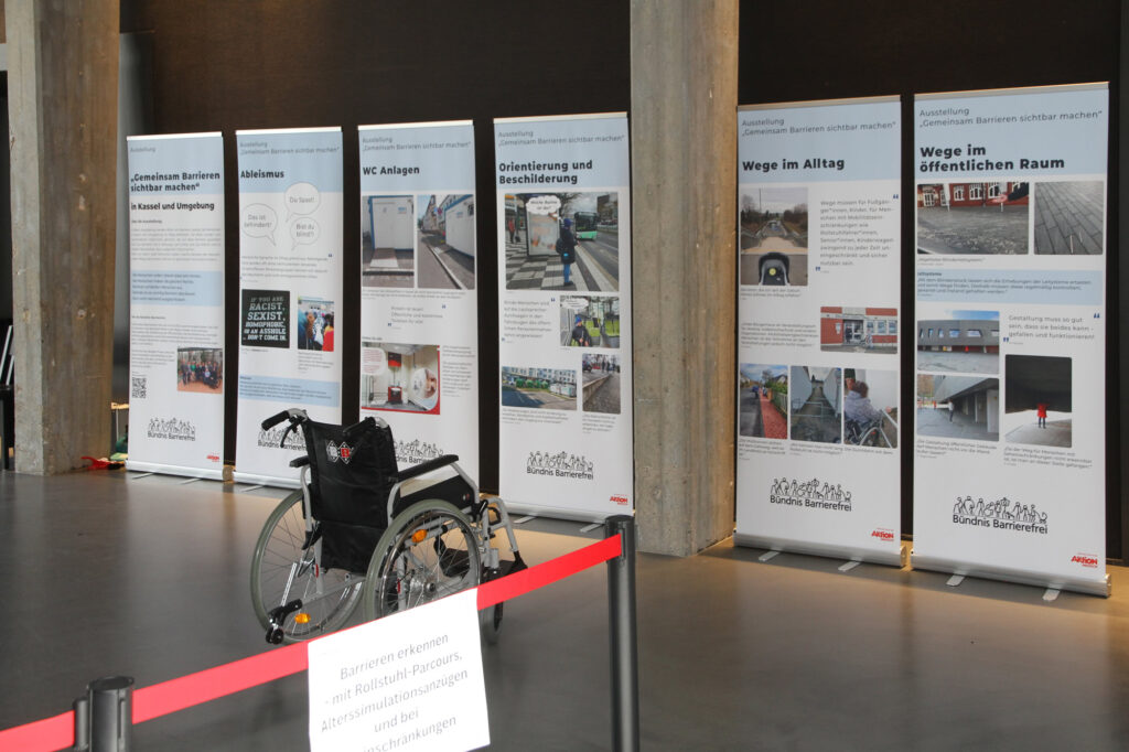 Ausstellungswand "Gemeinsam Barrieren sichtbar machen" zu den Themen Ableismus, WC-Anlagen, Orientierung und Beschilderung, Wege im Alltag, Wege im öffentlichen Raum