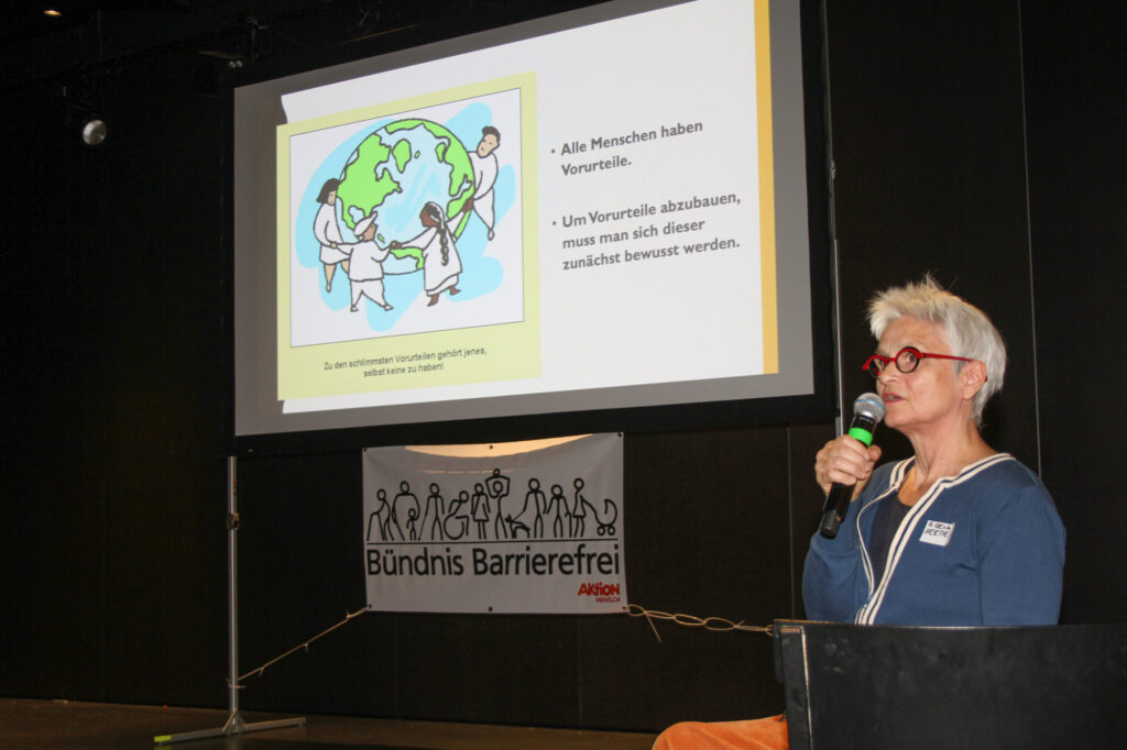 Gisela Hermes beim Vortrag. Auf dem Bildschirm hinter ihr steht: "Alle Menschen haben Vorurteile. Um Vorurteile abzubauen, muss man sich dieser zunächst bewusst werden. Zu den schlimmsten Vorurteilen gehört jenes, selbst keine zu haben."